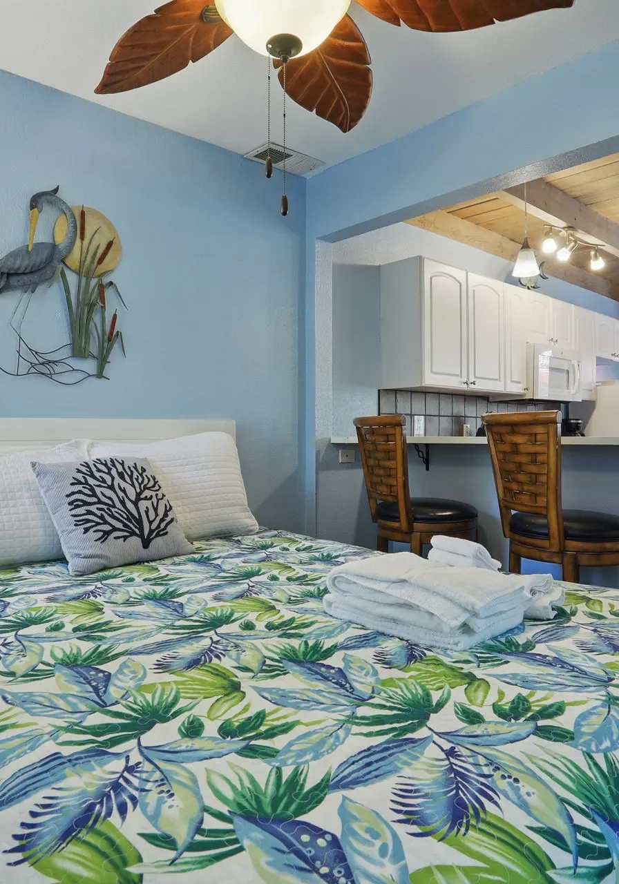 Cozy bedroom with tropical-themed bedding and ceiling fan.
