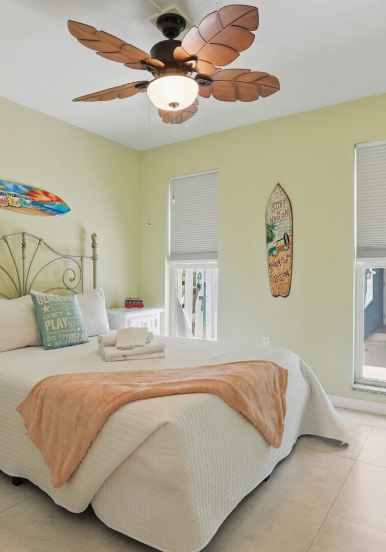 Cozy bedroom with beach-themed decor and ceiling fan.