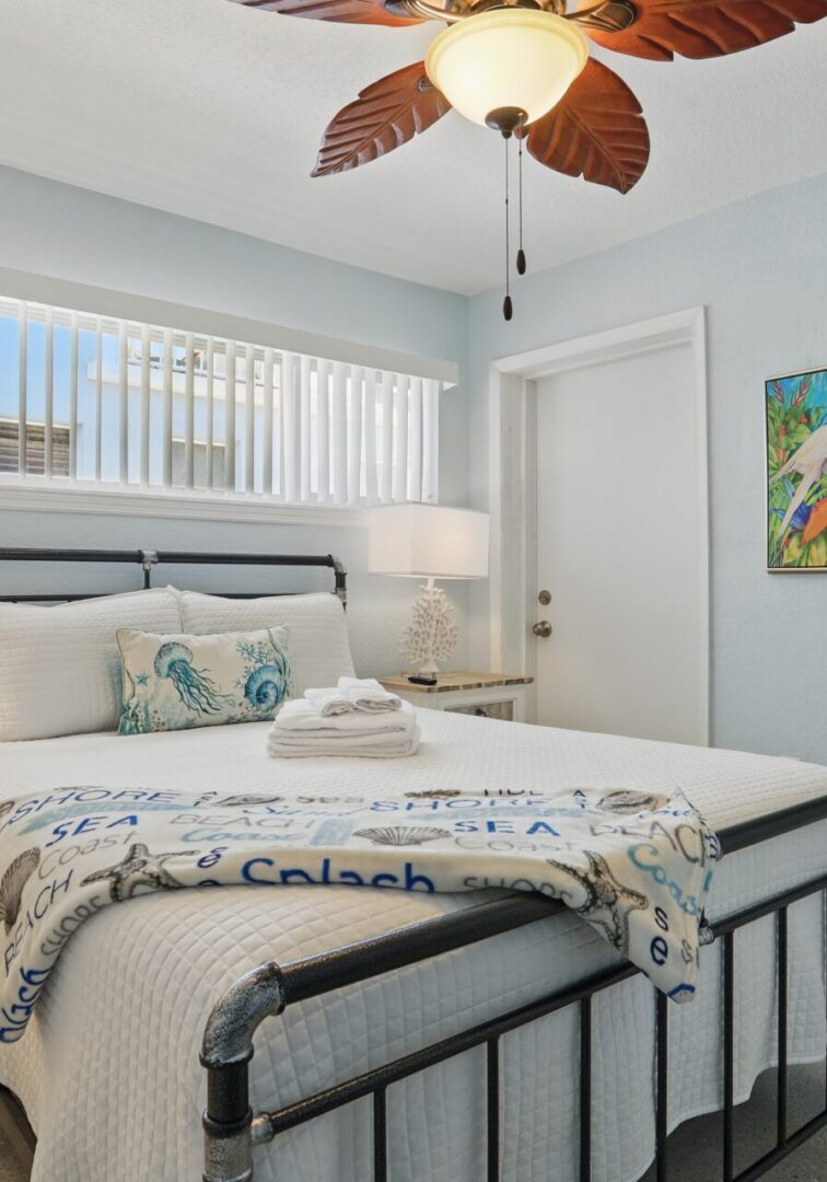 Bright bedroom with metal bed frame and tropical ceiling fan.