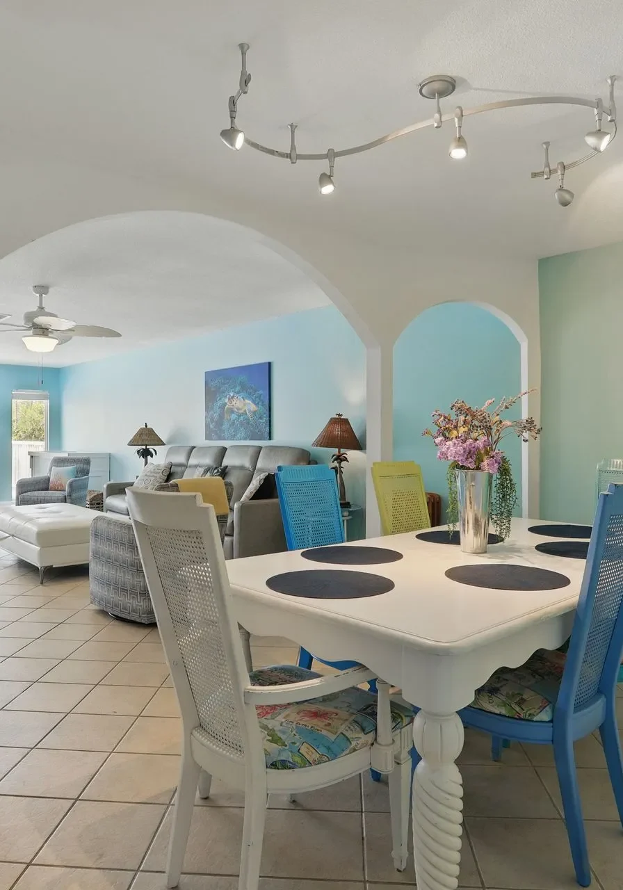 Bright dining area with a white table and turquoise chairs.